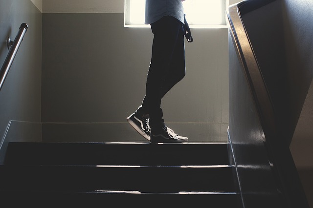 Muž v čiernych nohaviciach stojí na schodoch